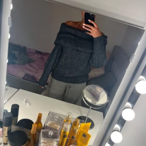 Mörkgrå offshoulder stickad tröja H&M - Supermysig mörkgrå stickad tröja från H&M med bred offshoulder-krage. Tröjan har lång ärm och ribbade muddar vid ärmslut och nederkant. Perfekt för dig som vill ha en chill men ändå snygg look under kyliga dagar.