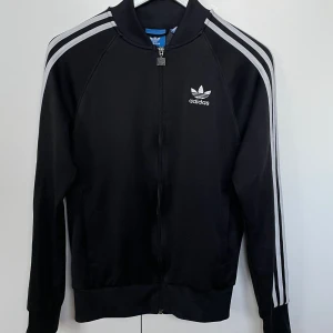 Adidas kofta  - Svart Adidas kofta med vita ränder.                             Fint skick