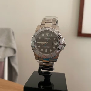 Seiko Mod Yacht Master - Stilren Seiko klocka i silver med automatisk urverk och datumvisning. Boetten och länken är i rostfritt stål, urtavlan är mörkgrå med tydliga index och siffror på vridringen. Klockan har sportig känsla och klassisk rund form. Äkta NH35 Urverk! 5 ATM