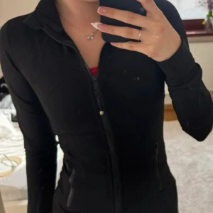  Lululemon Define Jacka Svart - Säljer en svart jacka från Lululemon med dragkedja framtill och figurnära passform. Jackan har länga ärmar och är tillverkad i ett mjukt, stretchigt material. Perfekt för träning eller en aktiv vardag. Helt ny! Hör av vid frägor!