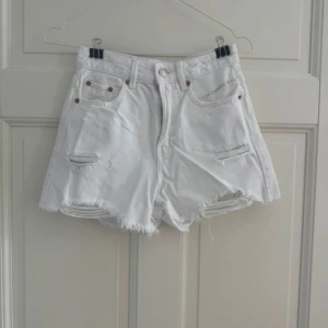 Vita jeansshorts från Stradivarius - Snygga vita jeansshorts från Stradivarius med hög midja och fransig, rå kant nertill. Shortsen har slitna detaljer framtill och klassiska fem fickor. Perfekta för sommardagar och ger en cool, avslappnad vibe.