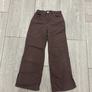 Bruna wide high waist byxor H&M - Snygga bruna byxor från H&M i wide fit med hög midja och justerbar resår i midjan. Byxorna är i 100% bomull och har klassiska fickor fram och bak. Perfekta för en chill och trendig look.