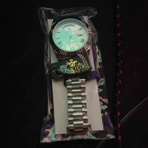 Silverfärgad Klocka  - Stilren klocka med silverfärgat armband i metall och klassisk rund urtavla. Urtavlan har romerska siffror och datumvisning. Perfekt accessoar för dig som vill ha en tidlös look.