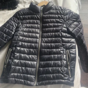 Svart quiltad pufferjacka med dragkedjor - Snygg mörkblå pufferjacka perfekt till hösten och vintern. Säljer då ja köpt liknande ny