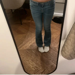 Blå bootcut jeans med låg midja - Säljer ett par snygga blå jeans med bootcut-modell och låg midja. Jeansen har klassisk femficksdesign, dragkedja och knapp framtill. Materialet är mjukt denim som sitter skönt och följer kroppen. Perfekta för dig som gillar en tidlös och avslappnad look. Mellan 155-170 cm. Oanvända 