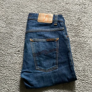Nudie Jeans W29 L30 - Snygga blå jeans från Nudie Jeansen som är i mycket bra skick och har använts fåtal gånger och passar riktigt bra nu till sommaren! Det är W29 L30 som du kan se på bilden och säljer det för att de är försmå! Pris kan diskuteras i snabb affär! 
