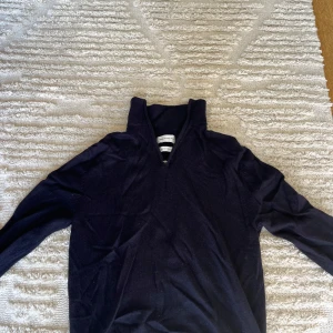 Mörkblå merinoull half zip tröja  - Mörkblå långärmad tröja från These Glory Days med half zip-dragkedja och hög krage. Tröjan är stickad i merinoull och har en clean, stilren look som passar perfekt till jeans eller chinos. Materialet känns mjukt och bekvämt mot huden.