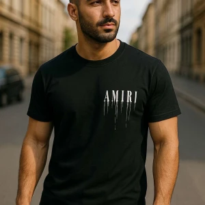 Svart Amiri t-shirt med tryck - Svart t-shirt från Amiri med korta ärmar och rund hals. Framsidan har Amiri-logga med droppande effekt i vitt och färg, medan baksidan pryds av en stor, silvrig ros och Amiri-tryck. Skön passform och riktigt snygg streetstil.