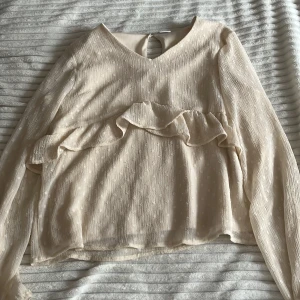 Superfin Blus från Lindex! - En jättegullig blus med volanger från Lindex, den har en knapp i ryggen. Blusen är Beige med ett prickigt mönster. Den är i Storlek 158-164 men passar mig som brukar ha XS/S 💗