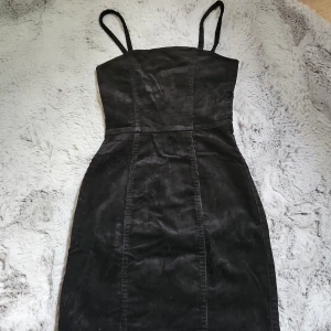 Svart manchesterklänning med dragkedja - Snygg svart kortklänning i manchester med smala axelband och figurnära passform. Använd fåtal gånger. Skriv om du har funderingar.