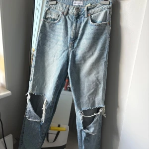 Ljusa ripped jeans från Zara - Säljer ett par ljusblå jeans från Zara med stora slitningar över knäna. Klassisk modell med raka ben.