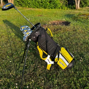 Gul och svart golfbag från Open - Golfbag från Open i sportig design med gula, svarta och vita detaljer. Utrustad med flera fack, dubbla axelremmar och praktiskt stativ för att stå stadigt på gräset. Tillverkad i slitstark syntet och polyester, perfekt för golfbanan. Sido facket är trasigt men det går att laga. Ny pris 1600 + driver för 600kr. Så erbjuder ett riktigt bra pris