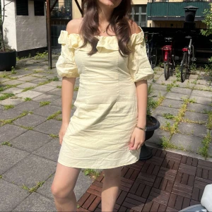 Gul offshoulder kortklänning med volang - Superfin ljusgul klänning med offshoulder och puffiga ärmar. Klänningen har en bred volang längs axlarna. Perfekt för sommarens alla tillfällen. Har bara använda en gång‼️