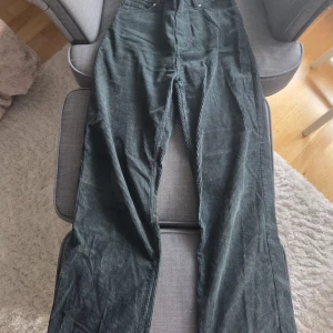 Gröna manchesterbyxor från Monki - Snygga mörkgröna manchesterbyxor från Monki i rak modell. Byxorna har klassiska fickor fram och bak, hög midja och breda ben. Perfekta för dig som vill ha en chill och trendig look med retrovibbar. Lite baggy vibes.