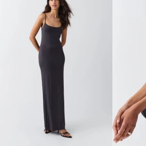 Långklänning från Gina Tricot - En stilren grå långklänning från Gina Tricot med smala axelband och figurnära passform. Klänningen har en enkel och clean look, perfekt för dig som gillar minimalistisk stil. Mjuk och stretchig känsla som sitter snyggt på kroppen.