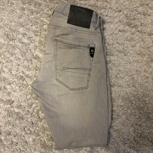 Grå Garcia jeans tapered fit - Snygga grå jeans från Garcia Jeans i modellen Russo Regular Fit med tapered ben. Jeansen har klassisk femficksdesign, normal midja och diskreta detaljer. Perfekta för dig som gillar en stilren look med smalare passform nedtill. Storlek W28 L30 