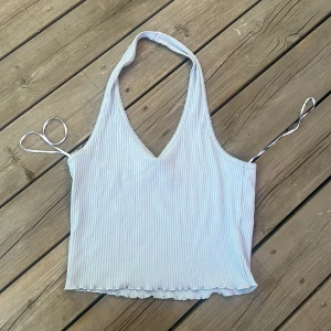 Ljusblå ribbad halterneck topp Bik Bok - Supersöt ljusblå ribbad halterneck topp från Bik Bok. Toppen har v-ringning, och halterneck hals och croppad passform med vågig kant nertill. Perfekt för varma dagar och snygg att styla med jeans eller kjol.