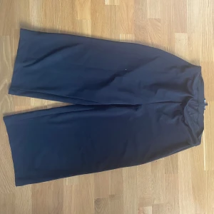 Svarta vida kostymbyxor - Snygga svarta kostymbyxor med riktigt vid passform och raka ben. Perfekta om du gillar en stilren och chill look. Byxorna har hög midja och är gjorda i ett mjukt tyg som känns skönt hela dagen. Inga fickor. Kan mötas upp i Trollhättan eller Alingsås. Kan skickas men då tillko en fraktkostnad.