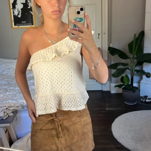 Vit spetsig oneshoulder topp från Mango - Superfin vit topp från Mango i spets med oneshoulder och volangdetaljer både upptill och nertill. Luftig och lätt med snygg struktur, perfekt till varma dagar. Säljs då den inte kommer till användning längre!