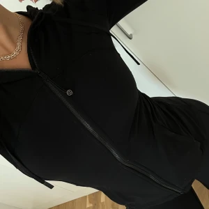 Lululemon jacka - Lululemon svart jacka Säljer en svart, sportig vindjacka med dragkedja framtill och huva med snörning. Jackan har långa ärmar och praktiska fickor. Perfekt för dig som gillar en clean och enkel stil när du är på språng.