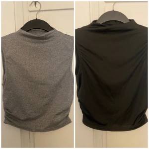2-pack ärmlösa polotoppar svart & grå - Två ärmlösa polotoppar i svart och grått, perfekta för layering eller träning. Båda har hög hals och stretchigt material, den grå har dessutom snygg rynkdetalj i sidan. Säljs som ett set.