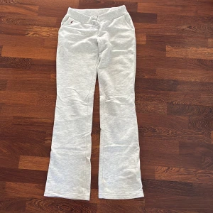 Grå mjukisbyxor LADICAH med stjärna XS - Grå mjukisbyxor från LADICAH i storlek XS. Byxorna har bootcut-snitt, resår i midjan med snörning och en stor vinröd stjärna baktill. Sköna och mjuka i bomullsmix, perfekta för chill dagar. Innebernslängd 86 cm.