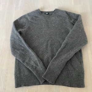 Grå stickad tröja från Uniqlo - Mysig grå stickad tröja från Uniqlo med rund hals och ribbade muddar vid ärmslut och nederkant. Liten i storleken. Perfekt för kyliga dagar och enkel att matcha med jeans eller chinos. Klassisk och stilren design som funkar till många olika looks.