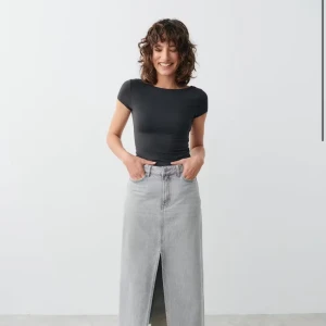 MörkGrå topp med öppen rygg - Säljer en mörkgrå, tight topp med korta ärmar och rund hals. Toppen har en riktigt snygg öppen rygg som ger en cool och trendig vibe. Perfekt att styla med jeans eller kjol för en stilren look. Materialet känns mjukt och följsamt mot kroppen.