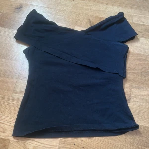 Svart offshoulder topp - Snygg svart offshoulder topp med asymmetrisk skärning. Perfekt för dig som gillar en stilren och trendig look. Det bara höra av sig om funderingar och så priset inte hugget i sten