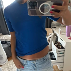 Blå kortärmad tröja - Snygg blå tröja med korta ärmar och rund hals. Modellen är enkel och passar perfekt till jeans eller shorts. Materialet känns mjukt och lätt, vilket gör den skön att bära under varmare dagar. Färgen är klarblå och ger en fräsch vibe.