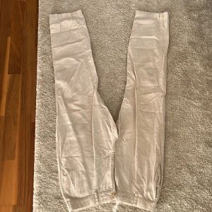 Beige linnebyxor från Uniqlo, stl S - Snygga beige linnebyxor från Uniqlo i storlek S. Byxorna har raka ben, resår i midjan och knäppning fram. Tillverkade i en skön mix av bomull och linne med lite stretch för extra komfort. Perfekta för en chill och stilren look.