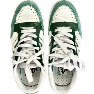 Vans sneakers i grönt och vitt - Snygga Vans sneakers i en fräsch kombo av grönt och vitt. Skorna har klassisk snörning, perforerad tå och detaljer i mocka och mesh. Den vita sula ger en clean look och det gröna V-märket på sidan gör dem extra coola. Perfekta för dig som gillar streetstyle.