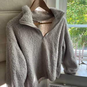 fluffig fleece half zip tröja - Supermjuk och fluffig beige fleece-tröja med halv dragkedja och hög krage. Perfekt för kalla dagar när du vill vara både varm och snygg. Långärmad och loose fit för extra mysfaktor.