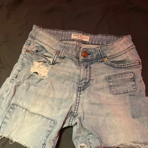 Ljusblå jeansshorts från Denim Gallery - Snygga ljusblå jeansshorts från Denim Gallery med slitna detaljer och råa kanter. Klassisk femficksmodell med knapp och dragkedja framtill. Perfekta för en chill sommarlook och passar till allt. Skinny fit och skön denimkänsla.