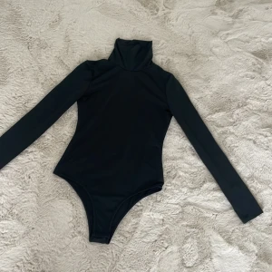 Body - En väldigt snygg långärmad body med polo krage, som går att klä upp och klä ner och passar till många olika tillfällen.