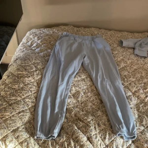 Ljusblå mjukis set från Vila XS - Supermysiga ljusblå mjukisbyxor och hoodiefrån Vila i storlek XS. Byxorna har resår i midjan och vid bensluten för en skön och avslappnad passform. Perfekta för chill eller när du vill vara bekväm hela dagen.