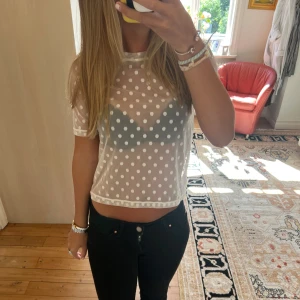 Vit meshig prickig croppad topp - Säljer en transparent vit meshig topp med prickigt mönster. Toppen är croppad och har korta ärmar. Perfekt för dig som vill ha en trendig och luftig look till sommaren. Superfin att styla med jeans eller kjol!💛