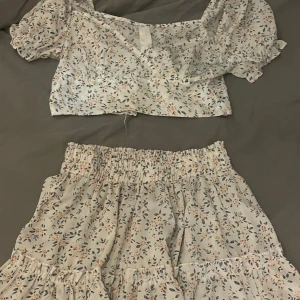 Blommigt sommar set - Supersöt kort kjol med blommigt mönster i ljusa toner. Med en matchade topp. Storlek S. Köptes för 149kr.