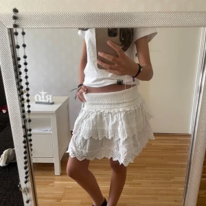 Vit volangkjol med broderade detaljer - Supersöt vit kortkjol med bred resår i midjan och flera lager volanger. Köpt på Bikbok i storlek XS