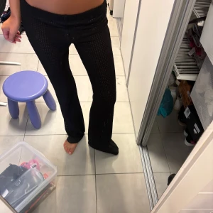 Svarta nätbyxor med bootcut - Säljer ett par svarta byxor i nätmaterial med bootcut-modell. Byxorna har en låg midja och är genomskinliga med ett coolt hålmönster. 