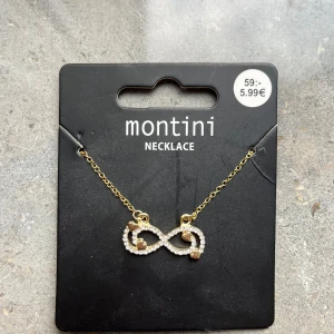 Guldigt halsband med infinitysymbol - Snyggt halsband från Ur & Penn med tunn guldfärgad kedja och ett hängsmycke i form av en infinitysymbol dekorerad med små gnistrande stenar och tre små hjärtan. Perfekt accessoar för att lyfta din look med lite extra bling.