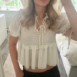 Superfin krämvit blus med knytning  - Nästintill helt oanvänd krämvit blus med knytning på armarna samt vid bröstet. Man kan göra en tajtare knut vid bröstet om man vill ha lite mer täckning men också lämna den öppen och till o med klippa av snöret om man vill det💕🌸