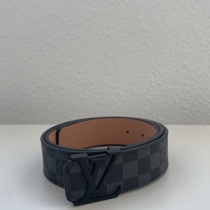  bälte - Snyggt  bälte i klassiskt Damier Graphite-mönster med svart märke. Bältet är gjort i exklusivt skinn med rutigt mönster i mörkgrått och svart. Insidan är ljusbeige och har präglad logga. Perfekt accessoar för att lyfta din outfit.