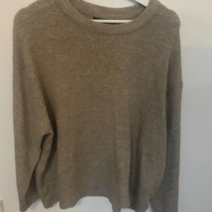 Beige stickad tröja från 157 - En enkel och snygg beige stickad tröja från 157 i storlek M. Tröjan har rund hals och långa ärmar med ribbade muddar. Perfekt för att hålla sig varm under kyliga dagar och passar till de flesta outfits.strl m. Går att pruta 