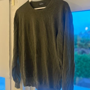 Olivgrön bomullströja Dressmann XL - Olivgrön långärmad tröja från Dressmann i storlek XL. Tillverkad av mjuk Supima bomull med rund hals och enkel design. Perfekt för dig som gillar stilrena och bekväma plagg. Passar dig som vill ha en normal passform och en chill look.