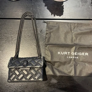 Svart Kurt Geiger mini Kengsington - Köpt på Plick för 1600kr, endast använd några gånger, repor i sidorna och hörnen men bra skick, dustbag ingår. 18cm bred, 14cm hög, 6cm djup, 60cm lång kedja, 32cm kedja vikt