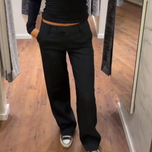 Svarta kostymbyxor från Bik Bok - Snygga svarta kostymbyxor från Bik Bok i storlek 34. Byxorna har raka, vida ben och klassiska fickor fram och bak. Perfekta för en clean och stilren look. Midjan är normal och materialet känns mjukt och följsamt.