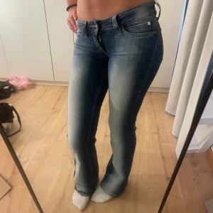 Blå bootcut jeans från cheap monday - Snygga blå bootcut jeans från cheap monday med ljusa slitningar framtill och bak. Jeansen har klassisk fickdesign, låg midja och utsvängda ben. Har väldigt liten slitning längst ned vid foten som inte syns om man inte kollar nära med ögat🥰