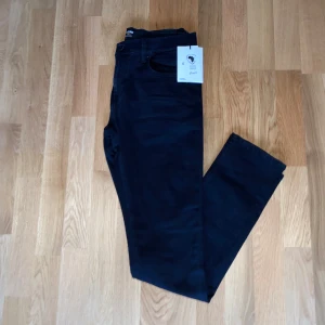 Svarta slim jeans från Jack & Jones - Snygga svarta jeans från Jack & Jones i slim fit-modell. Jeansen har klassisk femficksdesign, dragkedjegylf och är tillverkade i bomull med lite stretch för extra komfort. Perfekta för dig som gillar en stilren och enkel look. Helt oanvända 