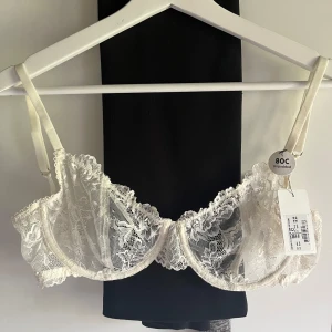 Vit spetsig bh från Kappahl  - Superfin vit bh från Kappahl med blommigt mönster och tunna justerbara axelband. Transparent mesh och vackra spetsdetaljer ger en romantisk vibe. Har aldrig använt och prislappen är kvar🌟 nypris 199kr💓